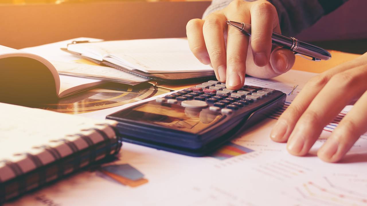 Imagem mostra mão feminina usando uma calculadora