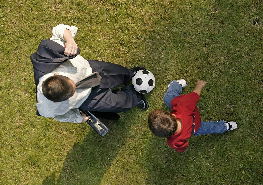 Vista superior de um homem brincando com uma criança com uma bola.